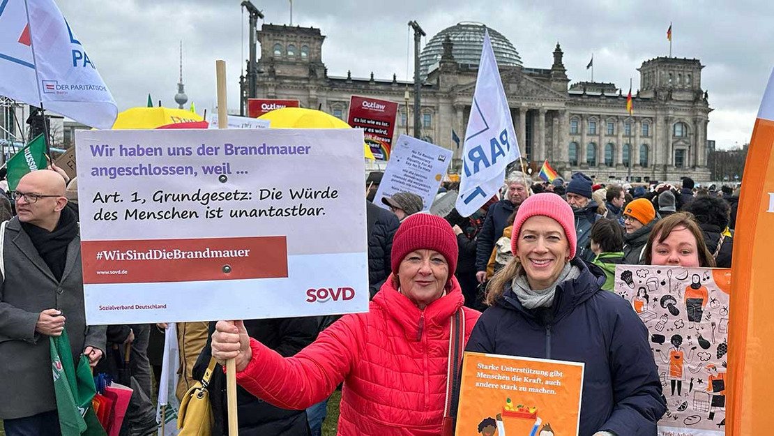 Frah hält SoVD-Plakat mit der Aufschrift "Die Würde des Menschen ist unantastbar". 